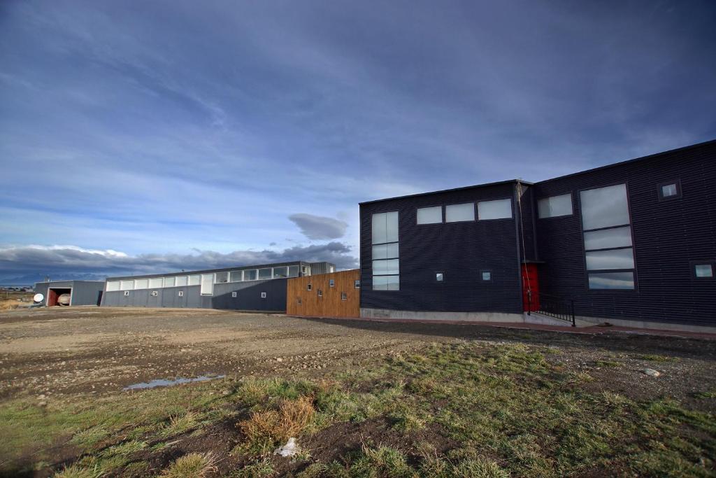 a building with windows on the side of a field at Appelgren House Hotel Boutique in Puerto Natales
