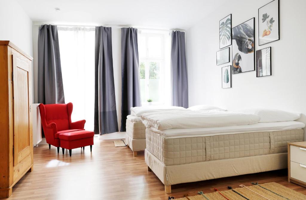 a bedroom with a bed and a red chair at Be in Berlin Apartments in Prenzlauer Berg in Berlin