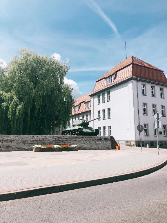 biały budynek z czerwonym dachem na ulicy w obiekcie Apartament Przy Deptaku w Drawsku Pomorskim