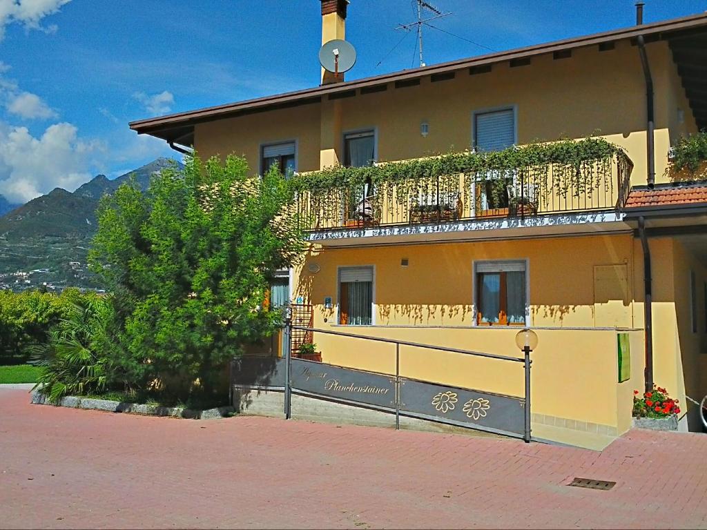 a yellow house with a balcony and a fence at Agritur Planchenstainer in Riva del Garda