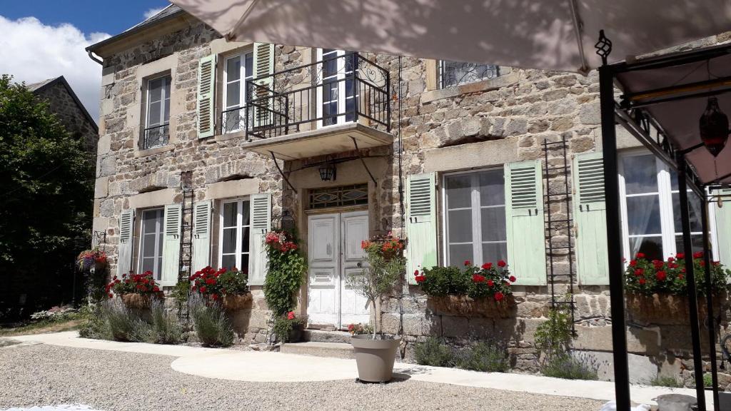 ein Steingebäude mit Blumen davor in der Unterkunft La Maison Bourgeoise in Saint-Priest-des-Champs