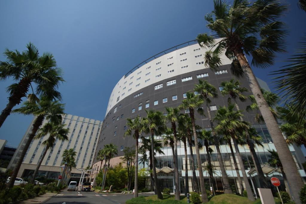 un edificio alto con palmeras delante en SPA&HOTEL EURASIA MAIHAMA en Urayasu