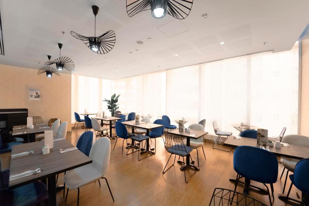 a dining room with tables and chairs and windows at Ibis Hong Kong Central & Sheung Wan in Hong Kong
