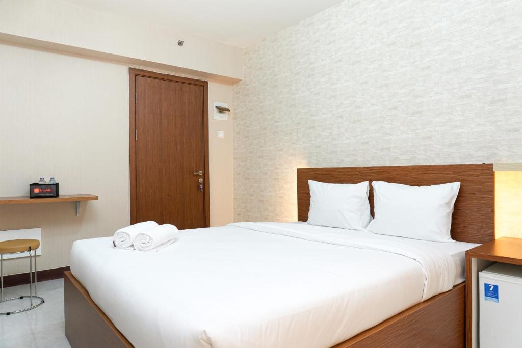 a bedroom with a large bed with white sheets at Modern Studio Apartment at Cinere Resort By Travelio in Depok