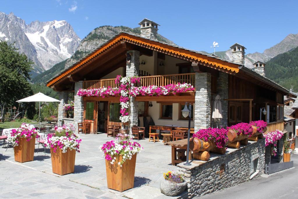 a building with flowers in front of it with mountains at Hotel Lo Campagnar in Courmayeur