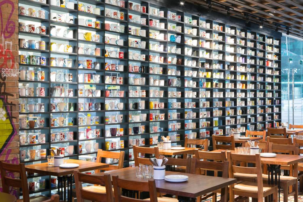 a restaurant with tables and chairs in front of a wall of books at The Sphere Serviced Residences Managed by HII in Manila