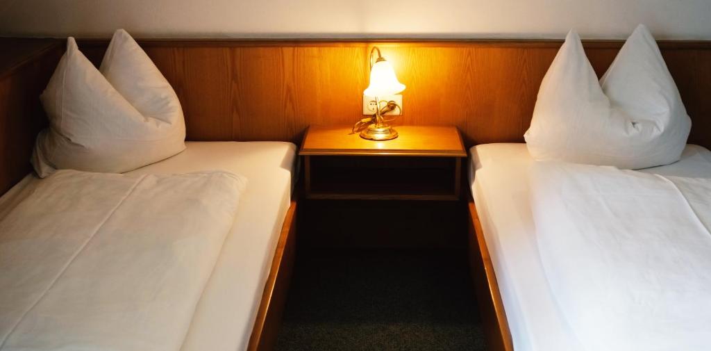 two beds in a room with a lamp on a table at Pension Rupertstubn in Ingolstadt