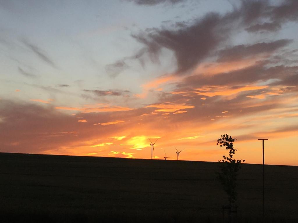 um pôr-do-sol com moinhos de vento numa colina num campo em Auszeit em Bell