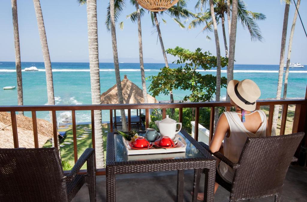 a woman sitting at a table with a plate of food at Villa Anjani - Ocean view Villa, With Private Garden and Cook - Candidasa in Candidasa