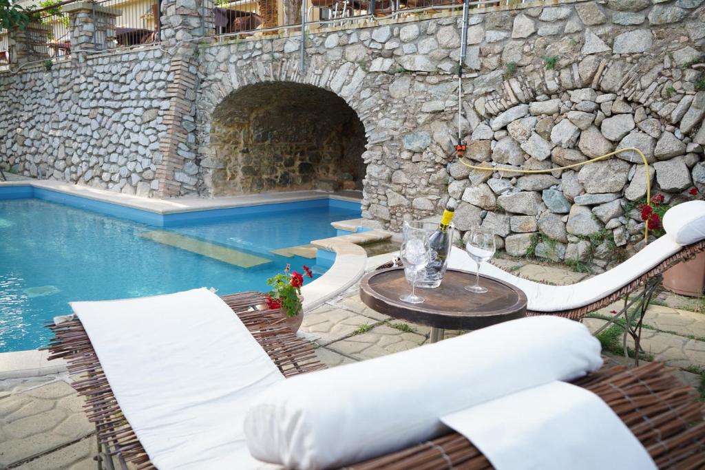 une piscine avec une table et des chaises ainsi qu'un mur en pierre dans l'établissement B & B Stillachiara, à Badolato