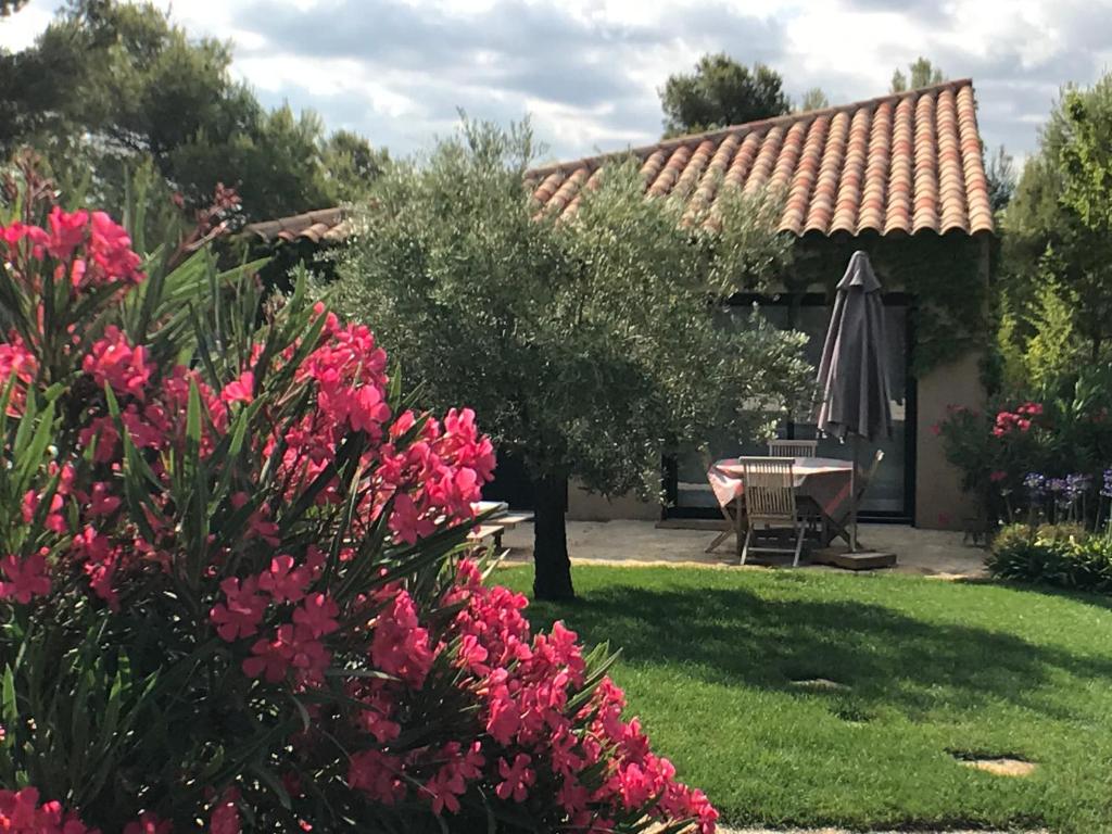 a garden with a table and an umbrella and pink flowers at Mer et Provence in La Cadière-dʼAzur