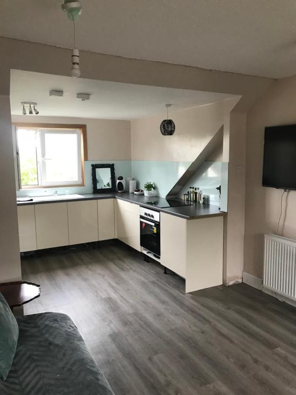 a kitchen with white cabinets and a flat screen tv at “A Wee Pad in Dunfermline” in Dunfermline