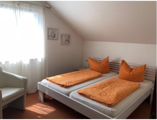 een slaapkamer met 2 bedden en oranje kussens bij Gasthof ´s Gräbele in Tübingen