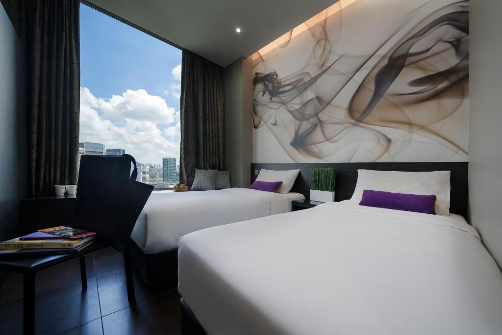 duas camas num quarto de hotel com uma grande janela em V Hotel Lavender em Singapura