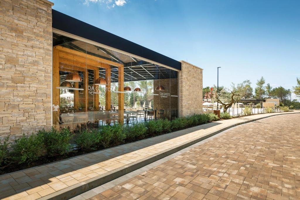a building with a brick facade and a sidewalk at Mobile Homes Camping Santa Marina, Lanterna in Poreč