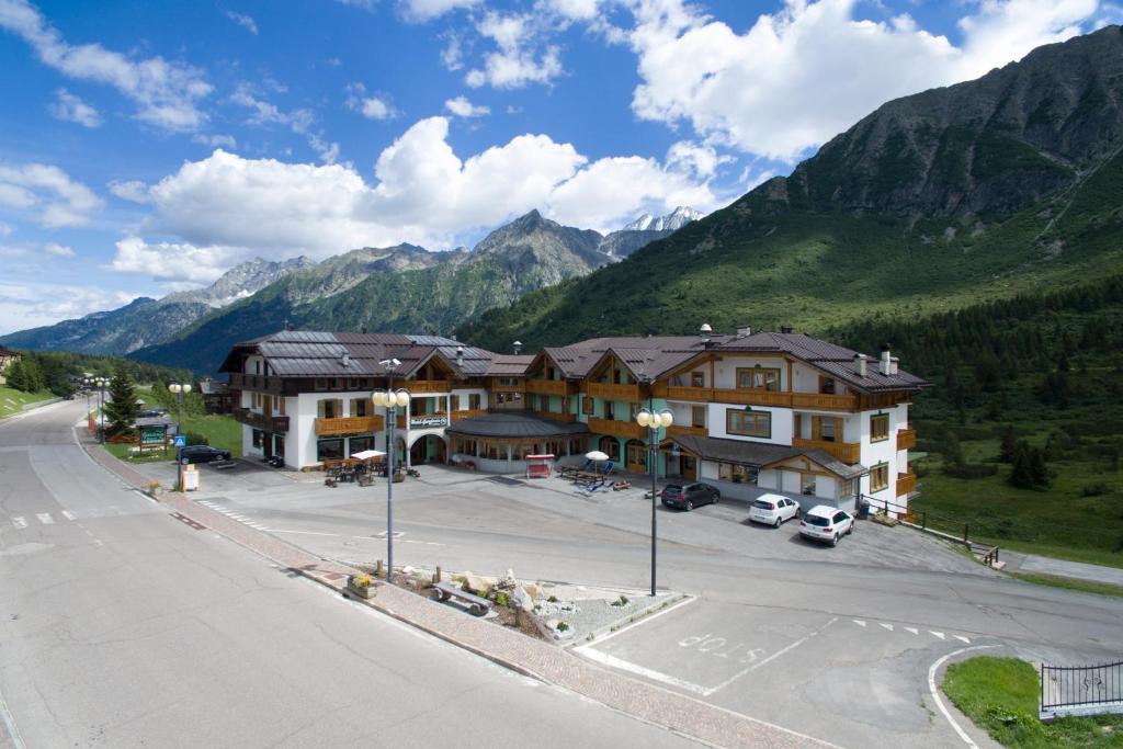an empty street in front of a building with mountains at Hotel Gardenia in Passo del Tonale