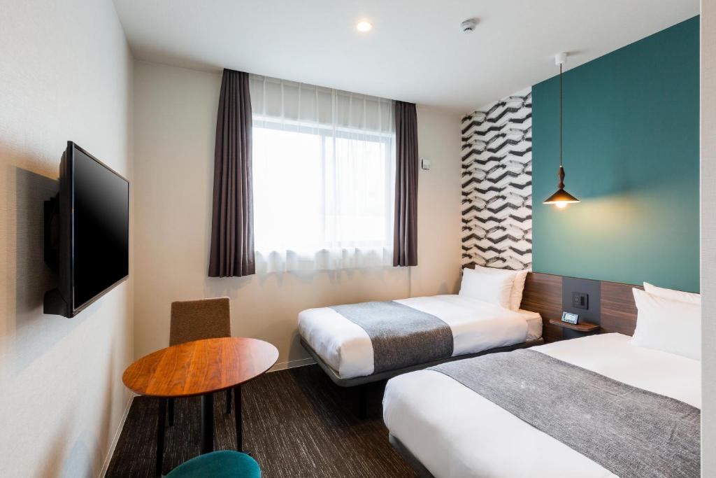 a hotel room with two beds and a television at M's Hotel Gojo Odawara in Kyoto