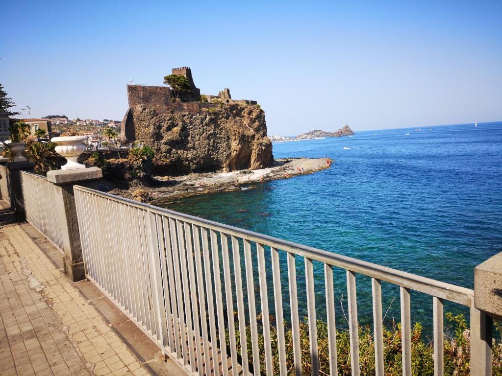 a white fence next to a body of water at Il Castello di Aci in Aci Castello