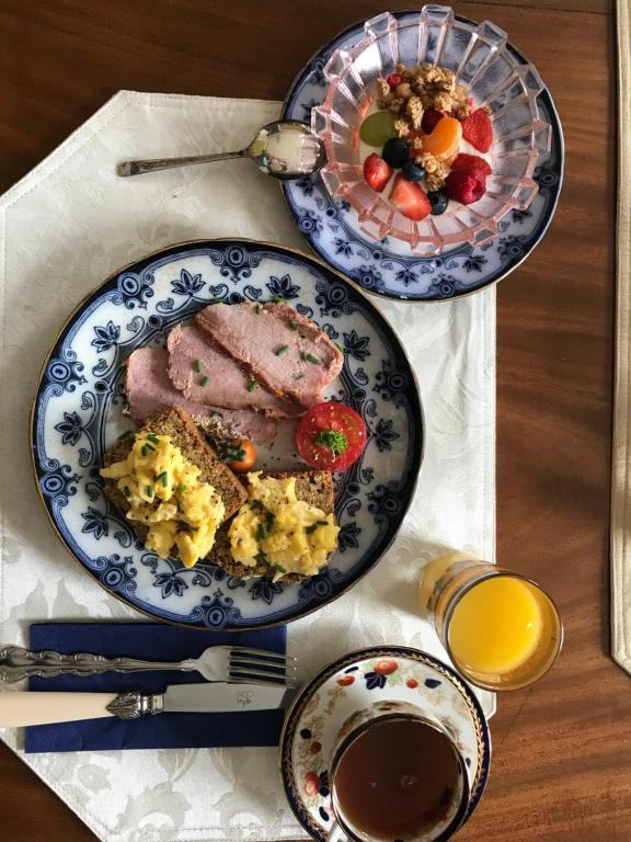 two plates of food with meat and a bowl of fruit at Gardenvale Manor House B&B in Stranocum