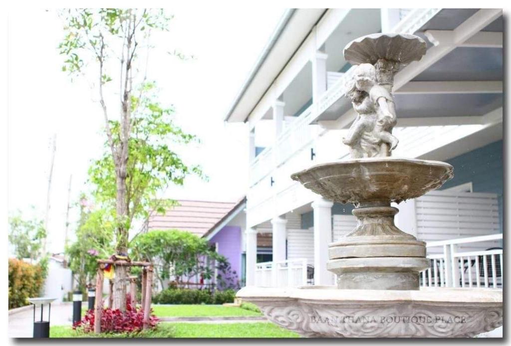 a fountain in front of a building with a statue at บ้านธนาบูติคโฮเทล in Surat Thani