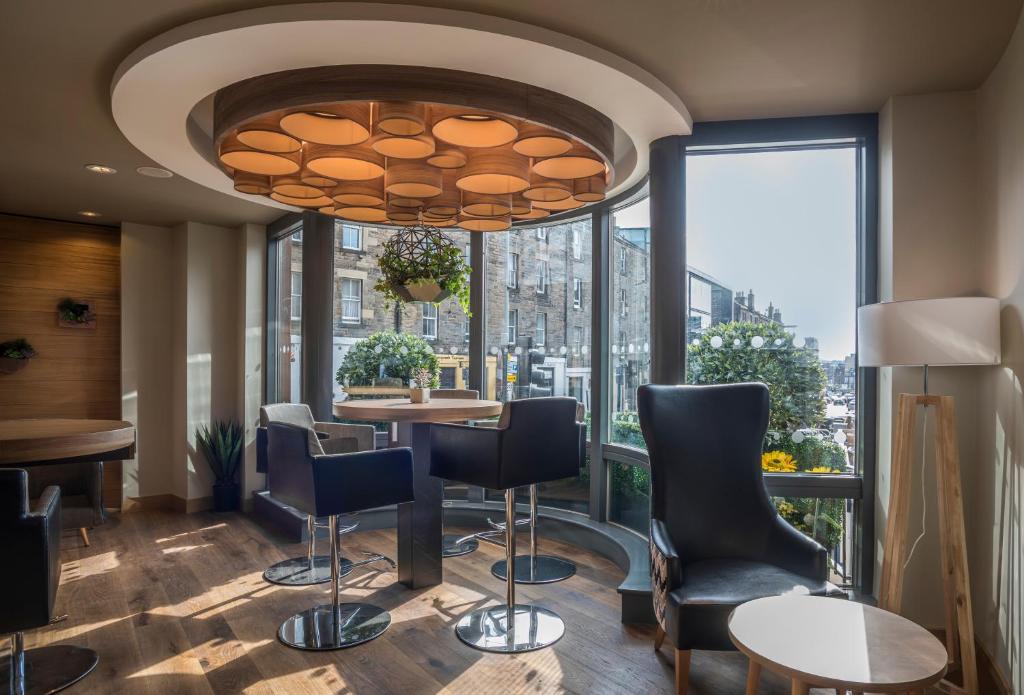 un ristorante con tavolo e sedie e una grande finestra di Point A Hotel Edinburgh Haymarket a Edimburgo