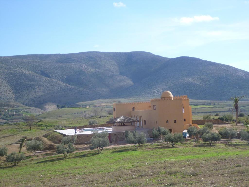 a large building in a field with mountains in the background at Gîte Raid Oriental in Taforhalt