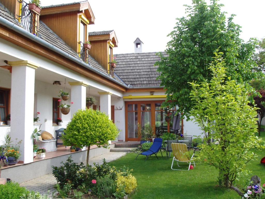 una casa con un patio con sillas y un árbol en Rudolf's Fogadó en Zsira