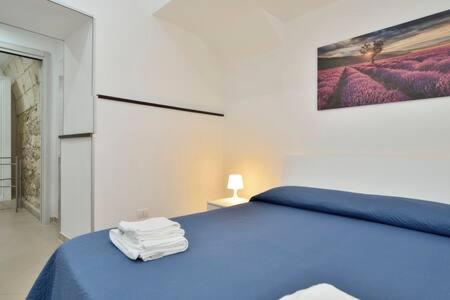 een slaapkamer met een blauw bed en een schilderij aan de muur bij ragusa curtigghiu in Ragusa