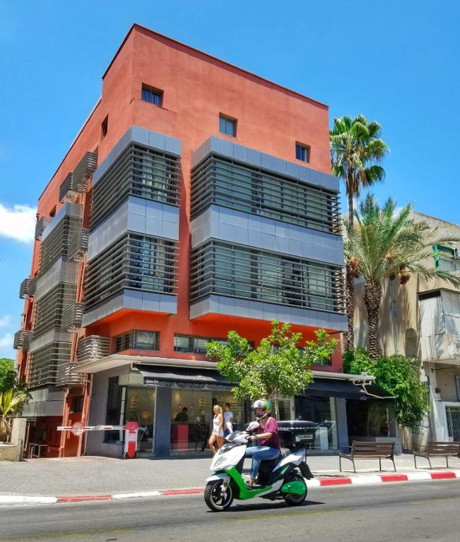 a man riding a scooter in front of a building at Ben Yehuda Apartments in Tel Aviv