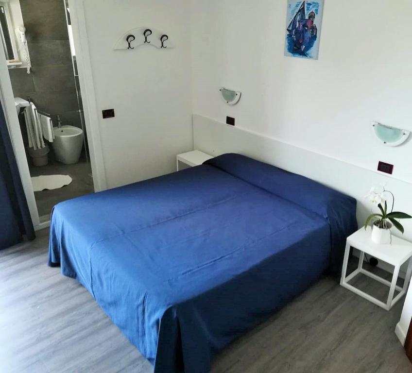 una camera con letto blu e un bagno di Hotel Friuli a Lignano Sabbiadoro