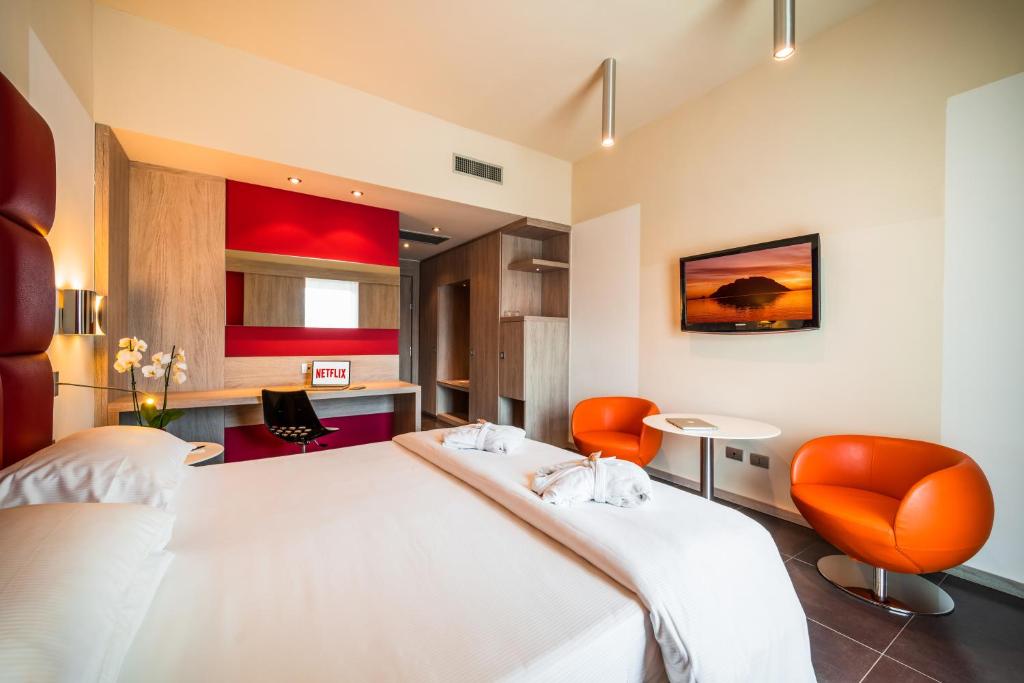 a bedroom with a large white bed and orange chairs at Jazz Hotel in Olbia