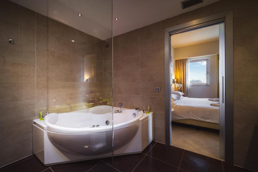 a bathroom with a bath tub and a bedroom at Jazz Hotel in Olbia