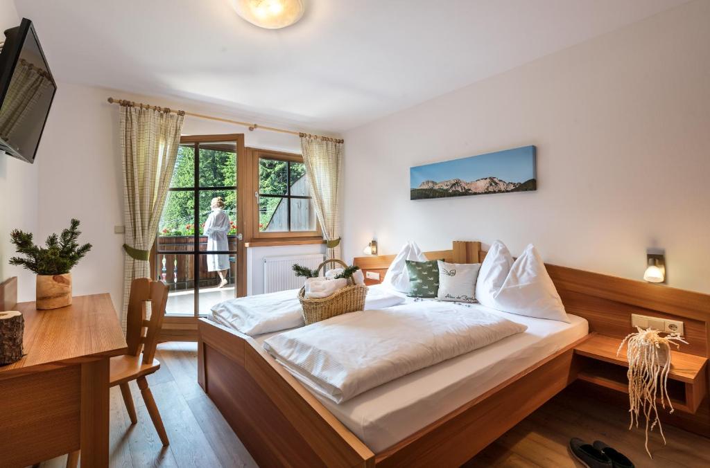 a bedroom with a bed and a desk and a window at Bar Garni Reischnhitt des Eschgfeller Christoph in Sarntal