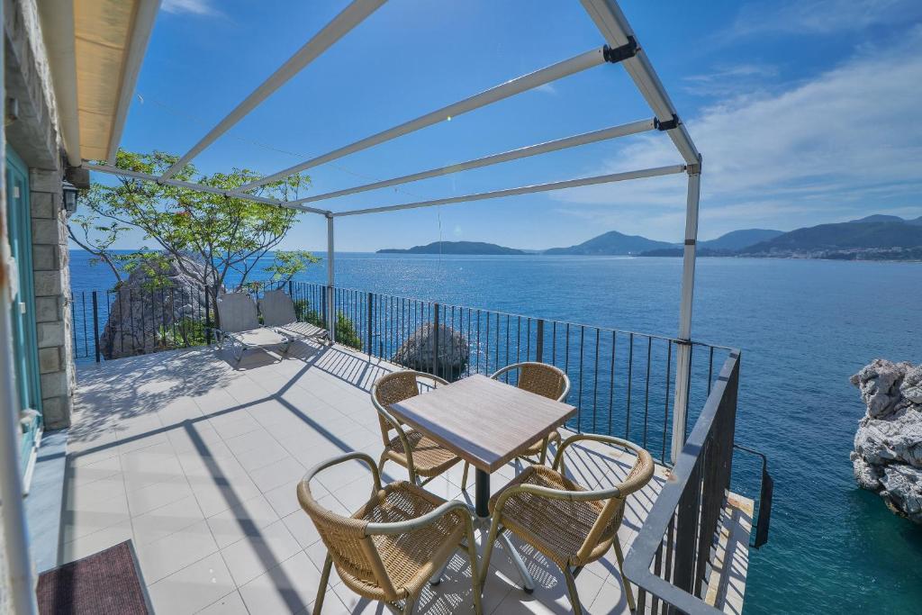 a table and chairs on a balcony overlooking the water at Kazanegra Exclusive Apartments in Sveti Stefan