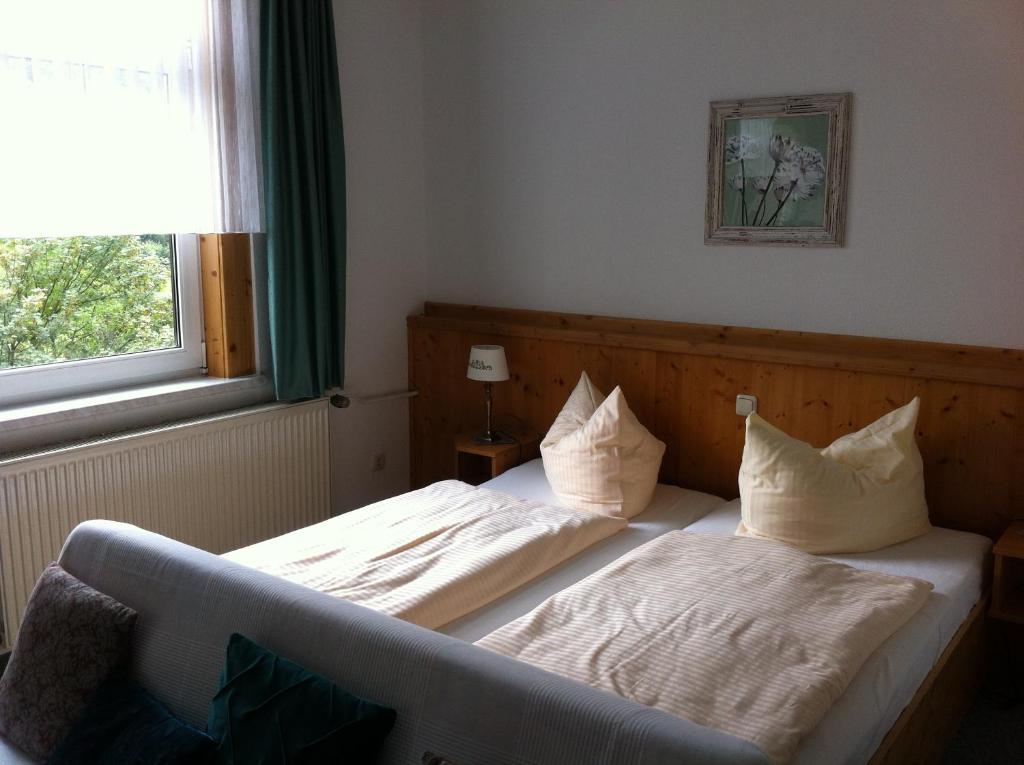 a bedroom with a bed with two pillows and a window at Pension Tannenrausch in Friedrichroda