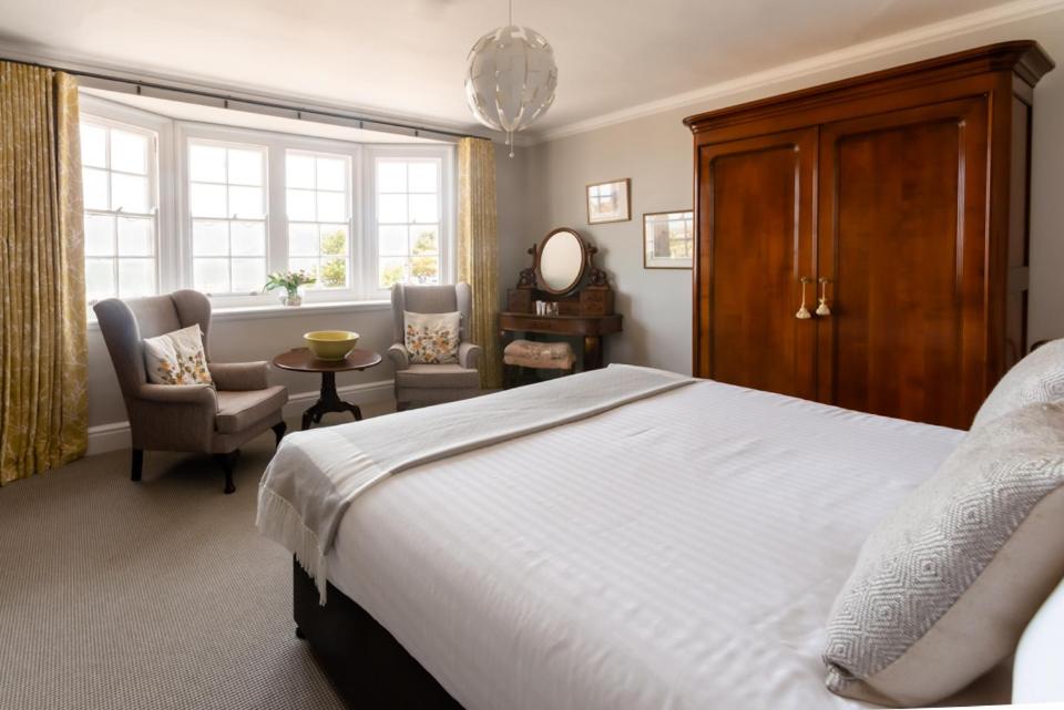 um quarto com uma cama, uma cadeira e uma janela em The Porlock Weir Hotel em Porlock