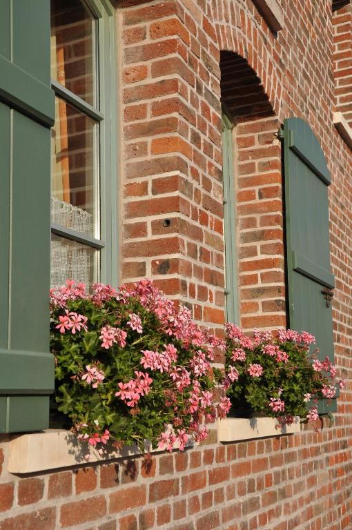 a window with flowers on a brick building at Grange de la Herde in Camon