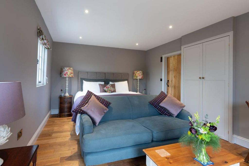 a living room with a blue couch and a bed at The Old Engineer A rural boutique retreat in Yalding