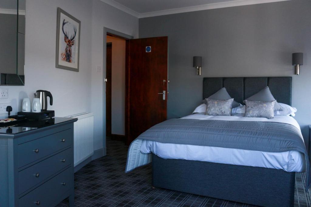 a bedroom with a large bed and a blue dresser at The Royal Hotel in Stranraer