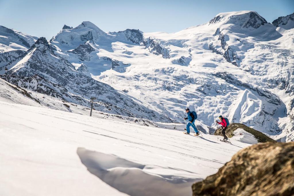 two people skiing down a snow covered mountain at Sunshine in Saas-Grund