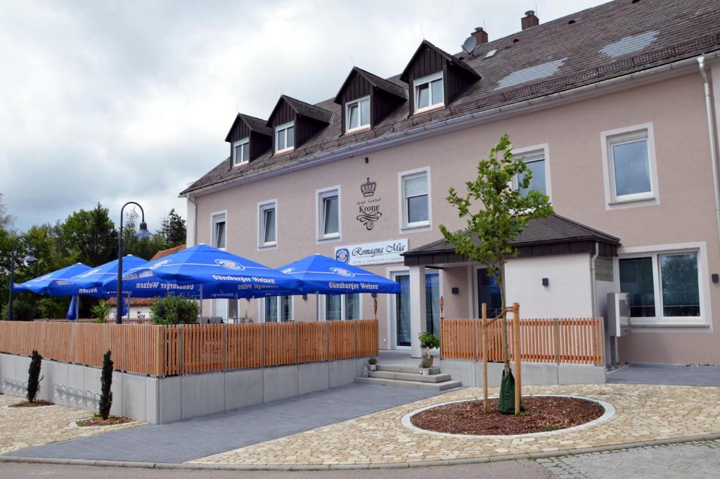 um edifício com guarda-chuvas azuis em frente em Romagna Mia - Hotel Ristorante Pizzeria em Nersingen