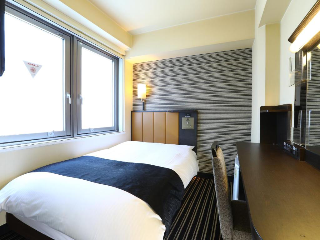 a bedroom with a bed and a desk and window at APA Hotel Shibuya Dogenzakaue in Tokyo