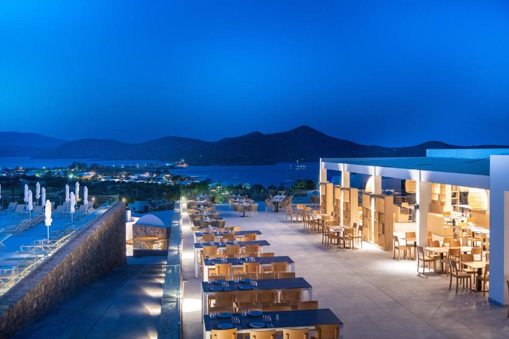 a hotel patio with tables and chairs at night at Elounda Breeze Resort in Elounda