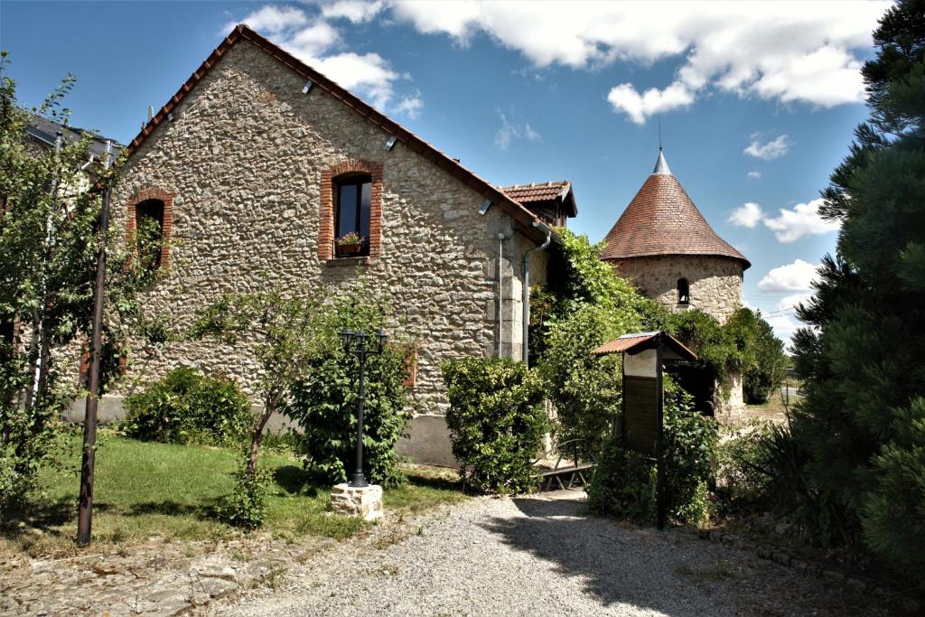 an old stone house with a turret and a driveway at Domaine de Vareilles in Vareilles
