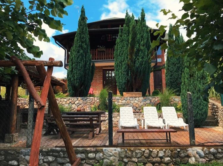 a group of chairs and a bench in front of a house at Holiday Home Drinsko svitanje in Gornja Trešnjica