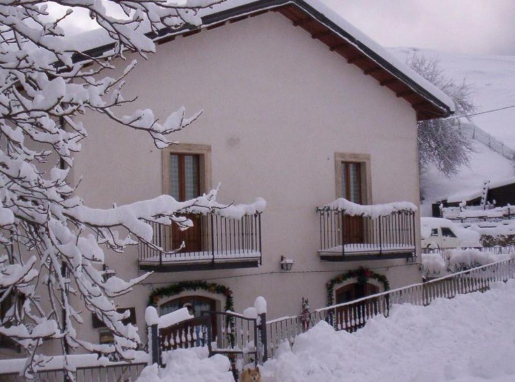 a house covered in snow with a fence at Le antiche Torri in Pescasseroli