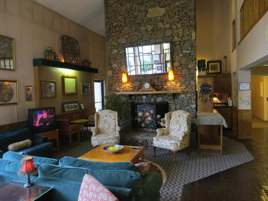 una sala de estar con sofás y una chimenea de piedra. en Americourt Hotel - Mountain City, en Mountain City