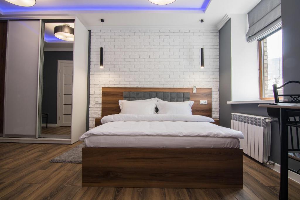 ein Schlafzimmer mit einem großen Bett und einer Ziegelwand in der Unterkunft LUX Apartment near Arena City in Kiew