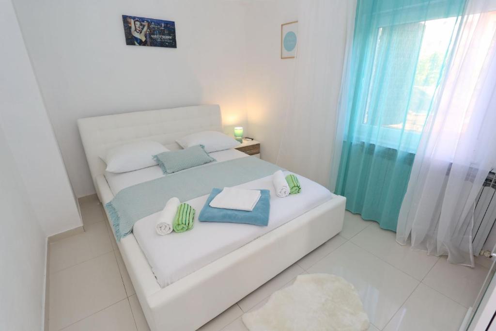 1 dormitorio con cama blanca y almohadas azules en Apartment Anna, en Zadar
