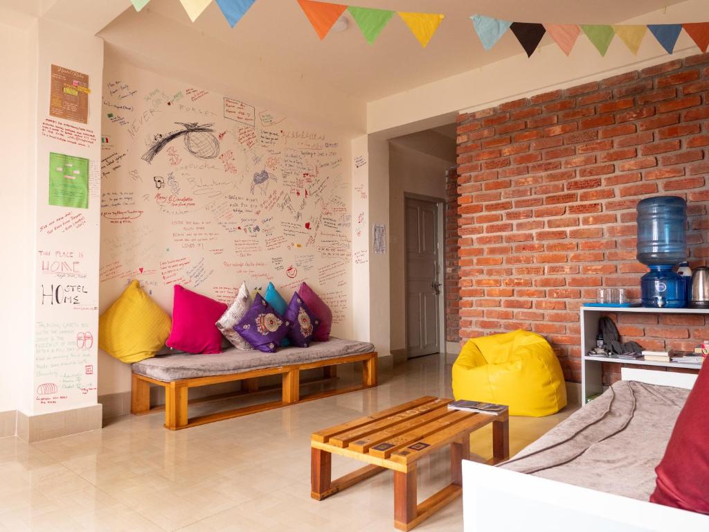 a living room with two benches and a wall with a mural at Tag Along Backpackers in Gangtok